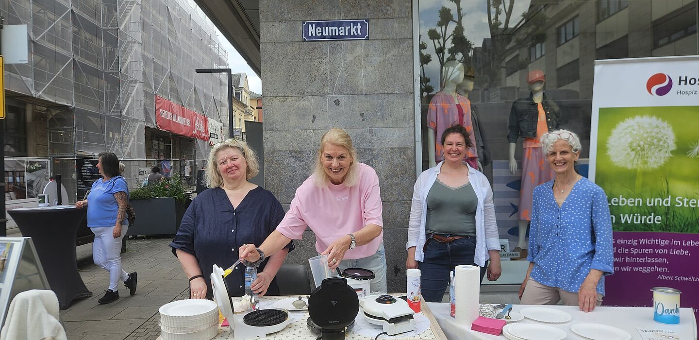 Vier Frauen stehen an einem Waffelstand in der Innenstadt von Limburg. 